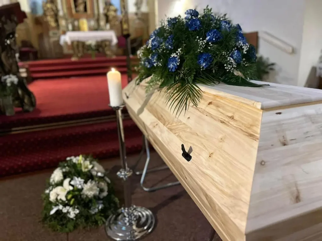 Detail dřevěné rakve s kyticí v obřadní síni